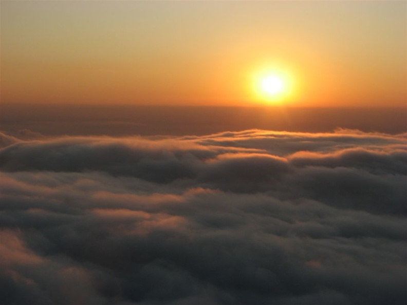 From Glacier View, the sun creates a golden sunset as it drops into a sea of clouds.