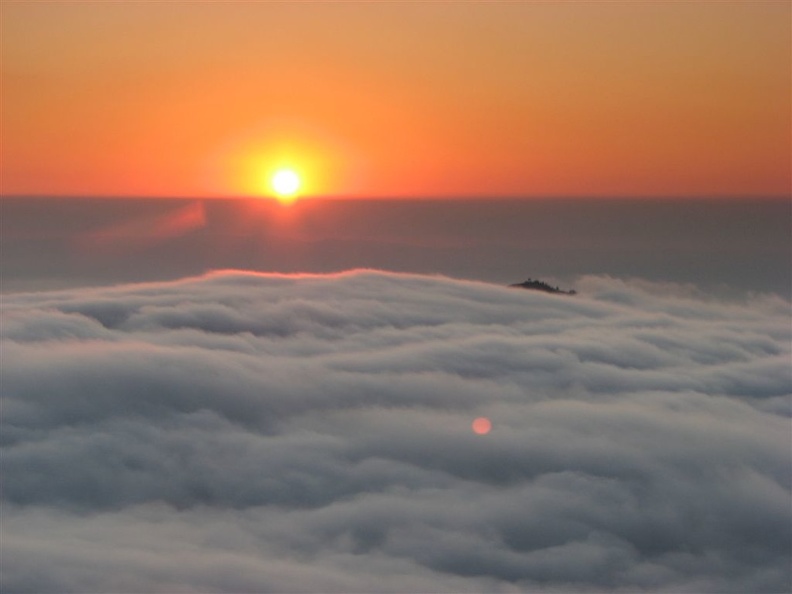 From Glacier View, the sun creates a golden sunset as it drops into a sea of clouds.