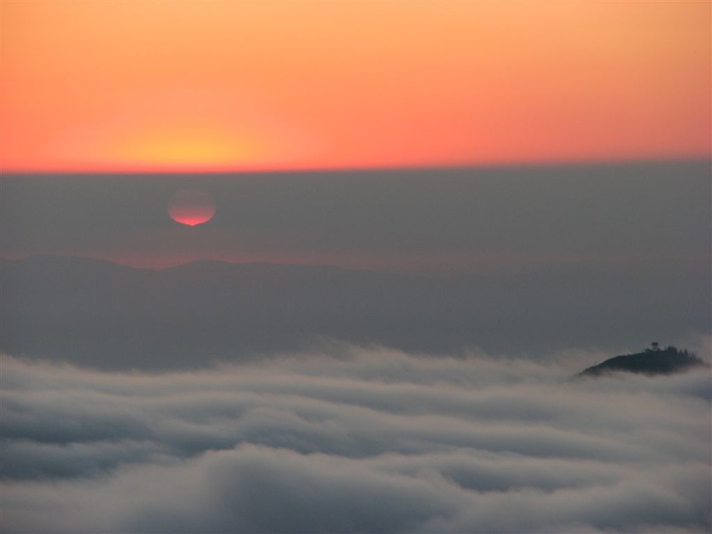 From Glacier View, the sun disappears into a fog bank and then shines through the fog above a sea of clouds.
