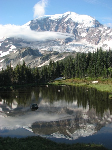 Mt. Rainier just after sunrise reflected in a meltwater pond. The marine air forms clouds as it flows over Mt. Rainer, then the clouds disappear again. An example of a mountain making its own weather.