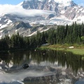 Mt. Rainier just after sunrise reflected in a meltwater pond. The marine air forms clouds as it flows over Mt. Rainer, then the clouds disappear again. An example of a mountain making its own weather.