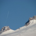 Closeup of Mt. Hood with a jet flying south leaving a contrail above Illumination Rock.